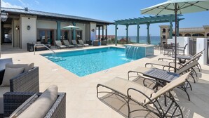 Ein Poolbereich mit Liegestühlen, einem kleinen Pool und einer Pergola mit Sonnenschirmen.