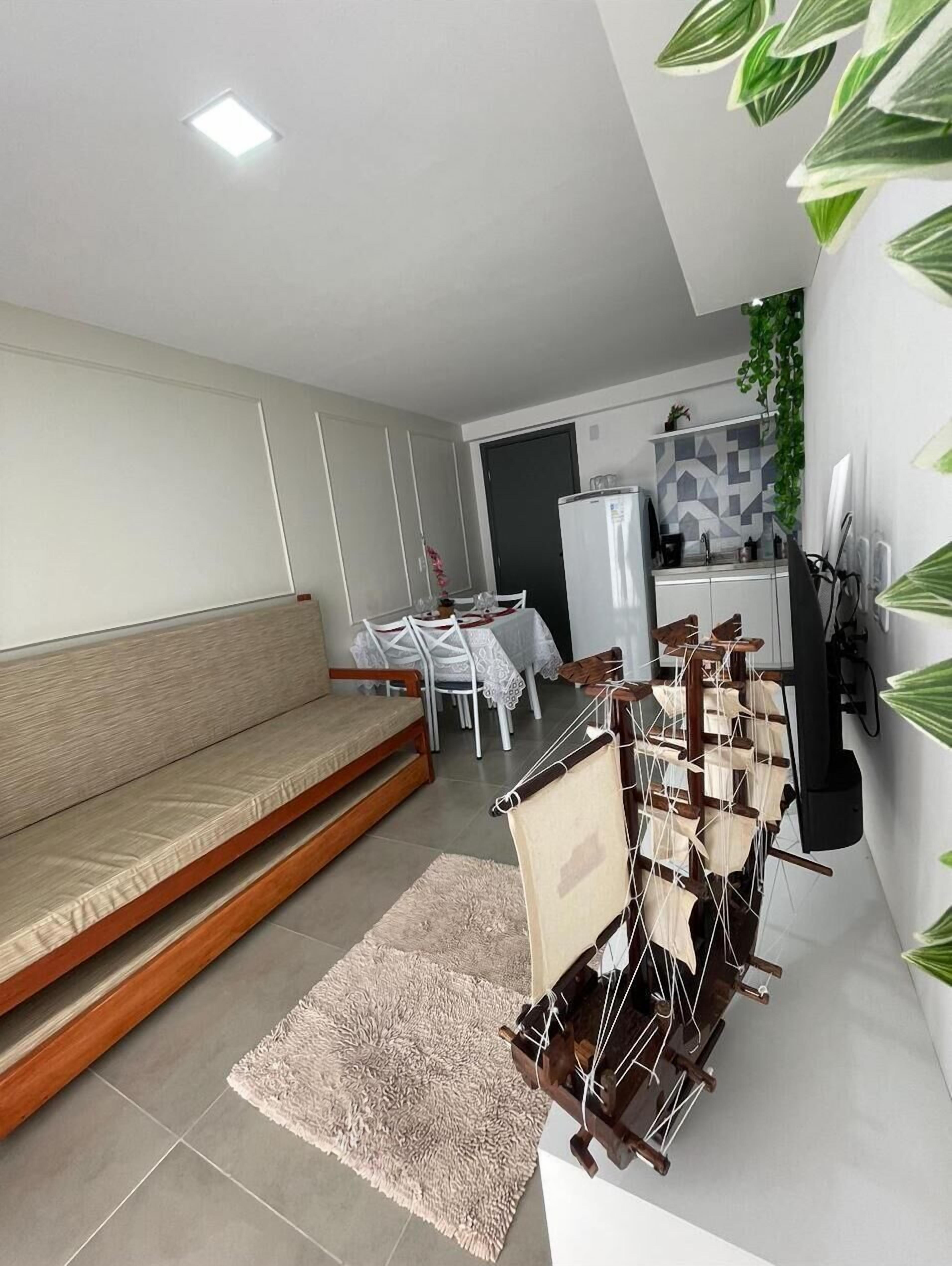 A modern living room with a sofa, a dining table, and a kitchen area in the background.