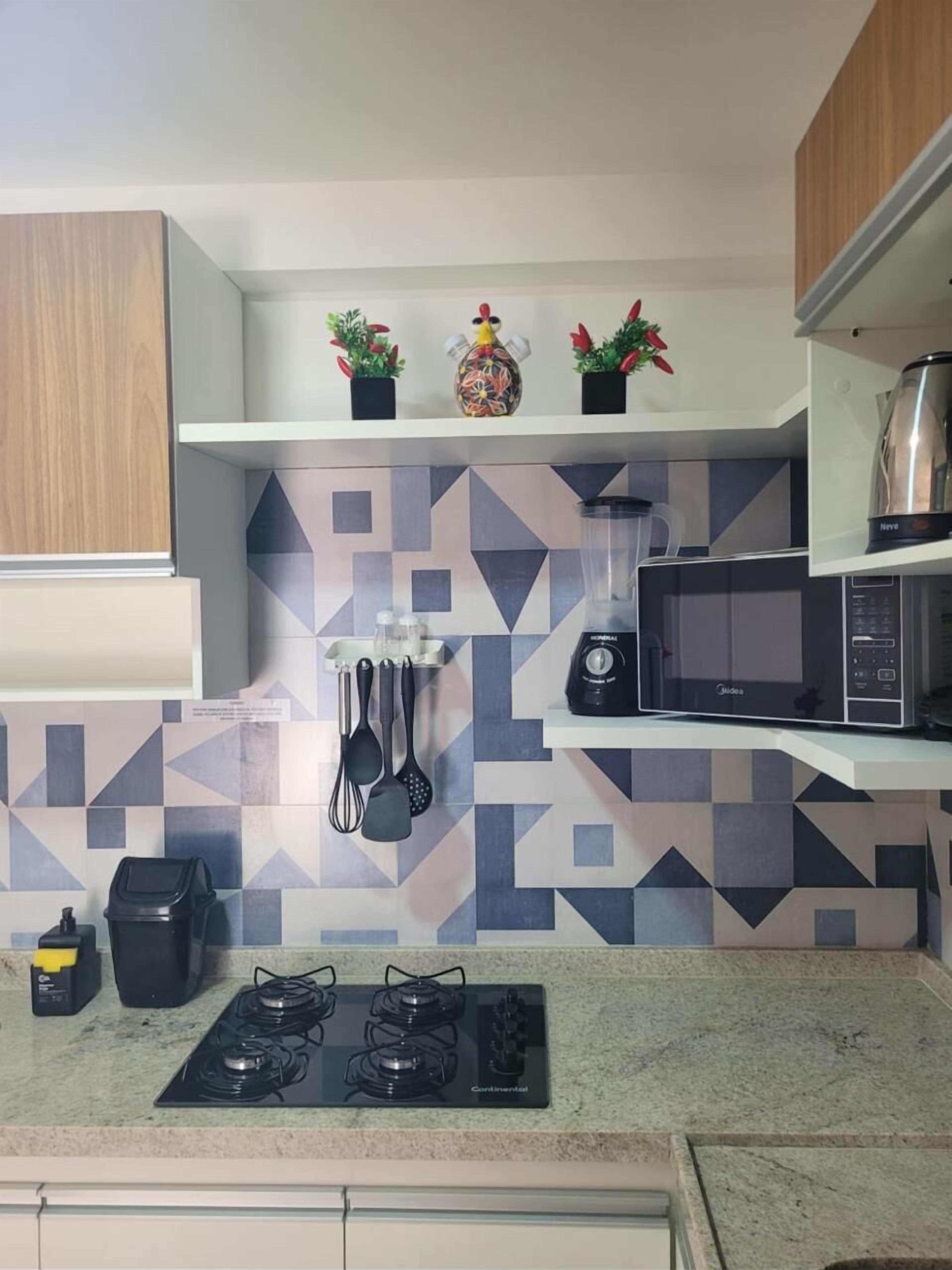A kitchen with a gas stove, microwave, and a shelf with potted plants.