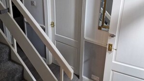 A staircase leading to a door with a mirror and a light switch on the wall. - 4 Bedroom Luxury Home with Garden in East London (Ilford)
