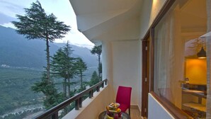 A balcony with a table set for dining, a chair, and a view of a mountainous landscape. - Aatmayog Luxury Manor Manali by Blueko Hotels (Manali)