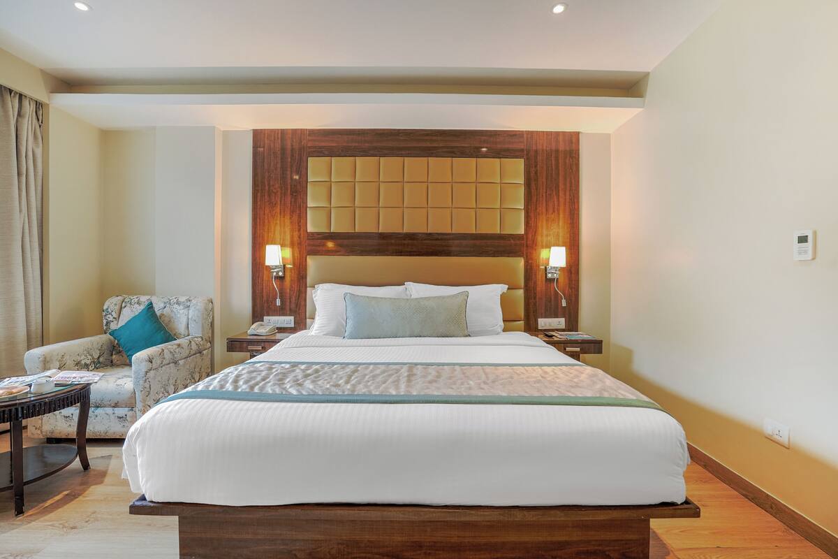 Ein Hotelzimmer mit einem großen Bett, einem Sessel, einem Nachttisch und einer Lampe.