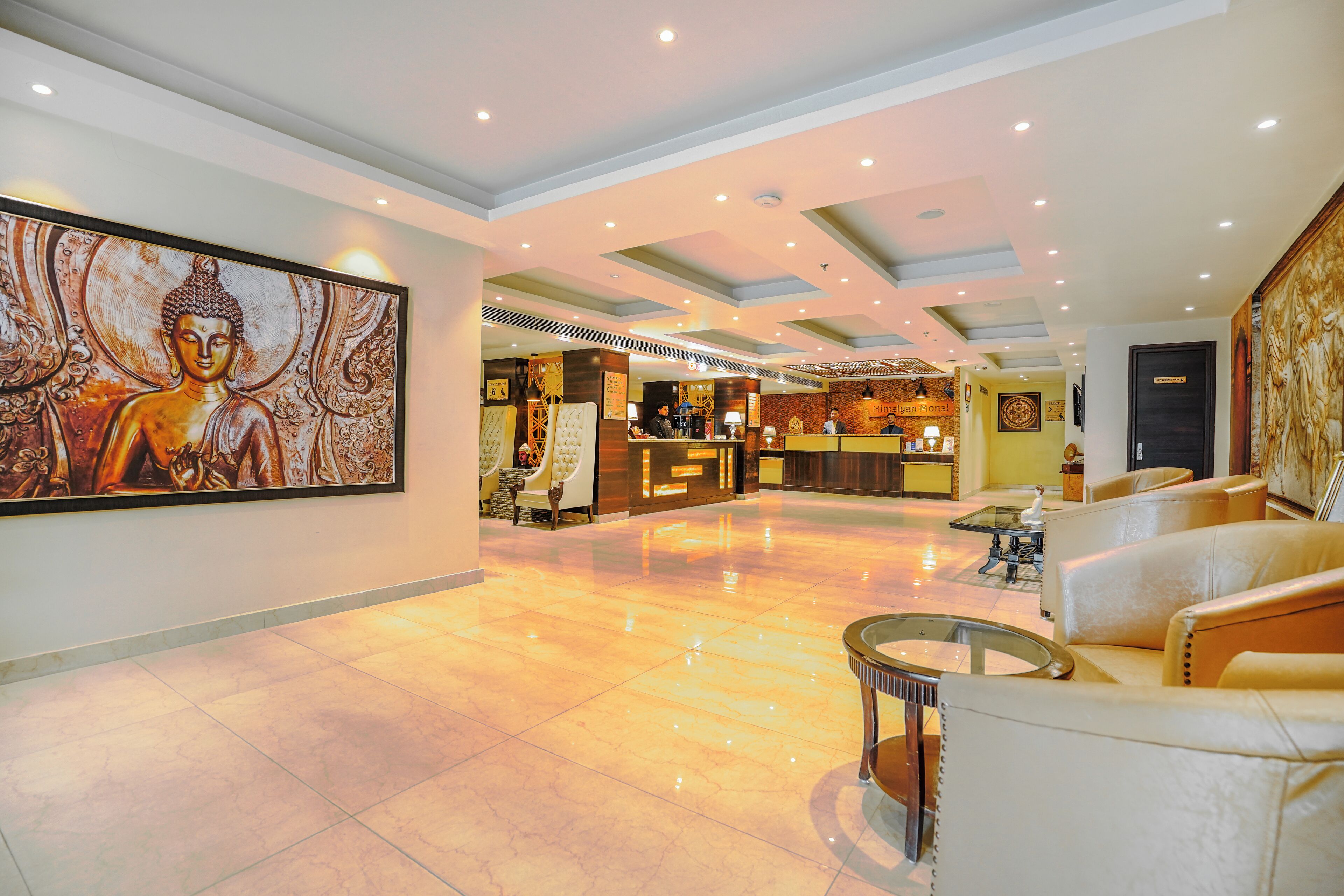A spacious lobby with a reception desk, seating area, and a large Buddha painting on the wall.