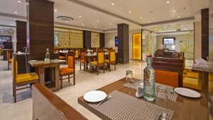 A hotel lobby with multiple dining tables and chairs, a reception desk, and a television screen. - Aatmayog Luxury Manor Manali by Blueko Hotels (Manali)