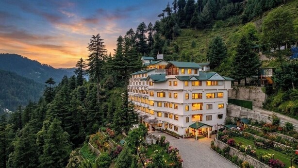 A multi-story hotel with a green roof, surrounded by lush greenery and mountains. - Aatmayog Luxury Manor Manali by Blueko Hotels (Manali)