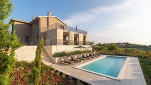 A modern house with a swimming pool, outdoor seating, and a stone facade.