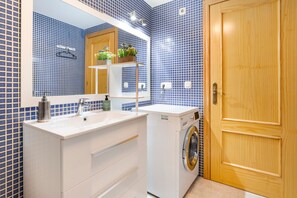 Ein Badezimmer mit Waschbecken, Spiegel und Waschmaschine.