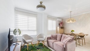 A living room with a sofa, chairs, a TV, a dining table, and a ceiling light. - Apartment 'El Corazon De Aguilas' with Wi-Fi and Air Conditioning (Águilas)