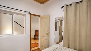Un dormitorio con una cama, una puerta de madera, un espejo y una ventana.