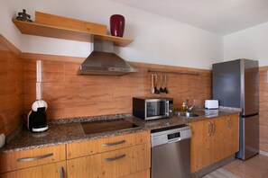 Una cucina moderna con piani in granito, mobili in legno ed elettrodomestici in acciaio inossidabile, inclusa una forno a incasso.