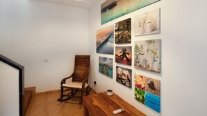 Un pasillo con una silla de madera, un banco y una pared decorada con diversas obras de arte enmarcadas.