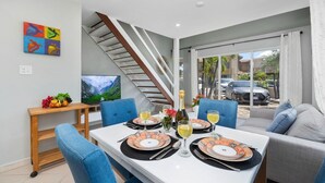 A dining area with a table set for four, a staircase, and a view of the outside.