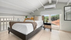 A bedroom with a bed, bedside table, and a view of the outside.