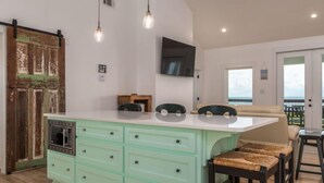 A kitchen with a large island, wooden cabinets, and a TV mounted on the wall. - New Listing "Somewhere at Sunset", 3 Bedrooms, 2 Baths, Waterfront, Sleeps 10 (Dauphin Island)