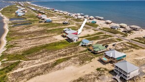 An aerial view of a coastal area with beach houses, a road, and a body of water. - New Listing "Somewhere at Sunset", 3 Bedrooms, 2 Baths, Waterfront, Sleeps 10 (Dauphin Island)