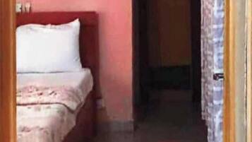 Un pasillo estrecho con una cama a la izquierda y una puerta al final.