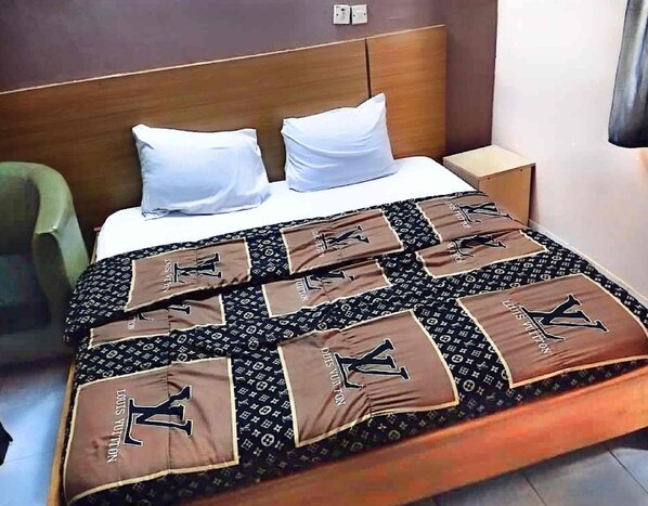 Une chambre d’hôtel avec un lit, deux oreillers, une table de chevet et une chaise.