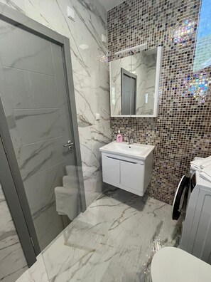 A bathroom with a marble floor, a white sink, a mirror, and a tiled wall. - Zauberhafte Apartment mit Meerblick in der Bucht von Kotor (Đenovići)