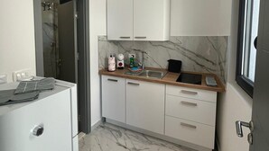 Eine kompakte Küche mit weißen Schränken, einer Marmor-Spritzschutzleiste und einem integrierten Geschirrspüler.
