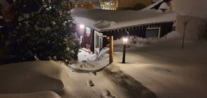 A snow-covered outdoor area with a wooden structure, a lamp post, and a tree.