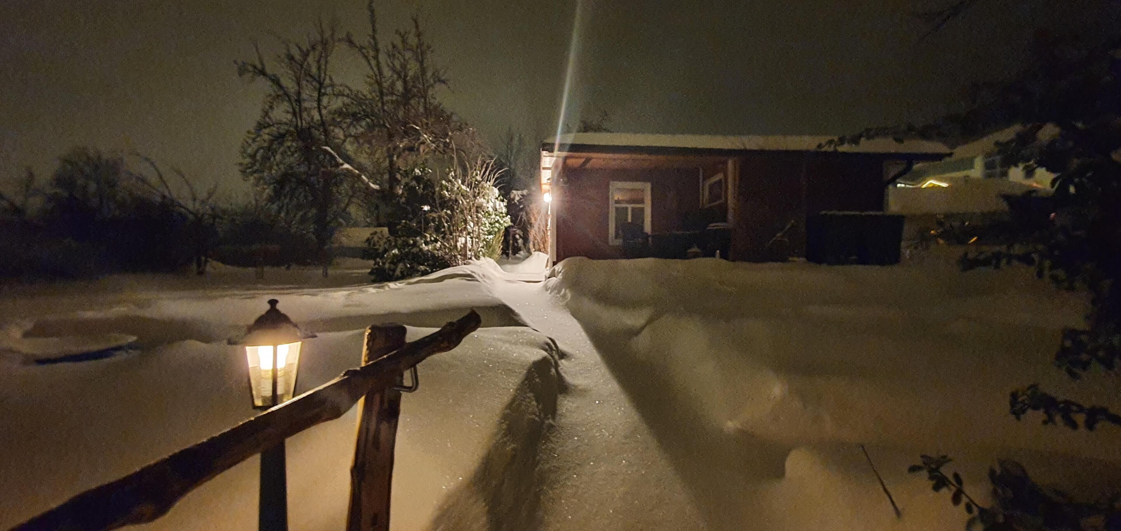 A snow-covered path leading to a house with a visible door and windows.