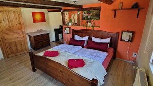 A bedroom with a wooden bed, a wooden dresser, a desk, and a window with a view. - Ferienwohnung Fliegenpilz - 50m² OG1 (Quedlinburg)