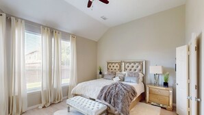 Un dormitorio con una cama grande, un banco, una mesita de noche y una puerta.