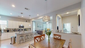 Una cocina moderna con armarios blancos, una isla central y taburetes de bar.