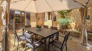 An outdoor patio with a table and chairs, surrounded by a pergola with string lights. - Villa Le Bos - Three Bedroom Villa, Sleeps 6 (Pezuls)