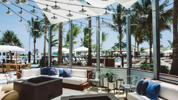 An outdoor seating area with a pool view, palm trees, and umbrellas.