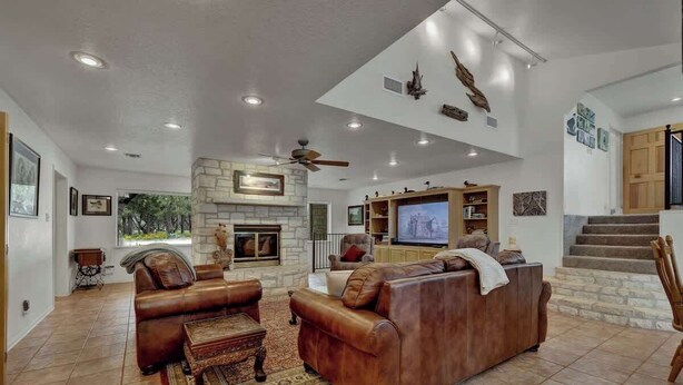A spacious living room with leather sofas, a fireplace, a television, and a staircase.
