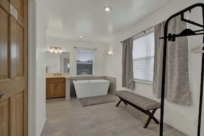 A modern bathroom with a bathtub, vanity, and a bench.