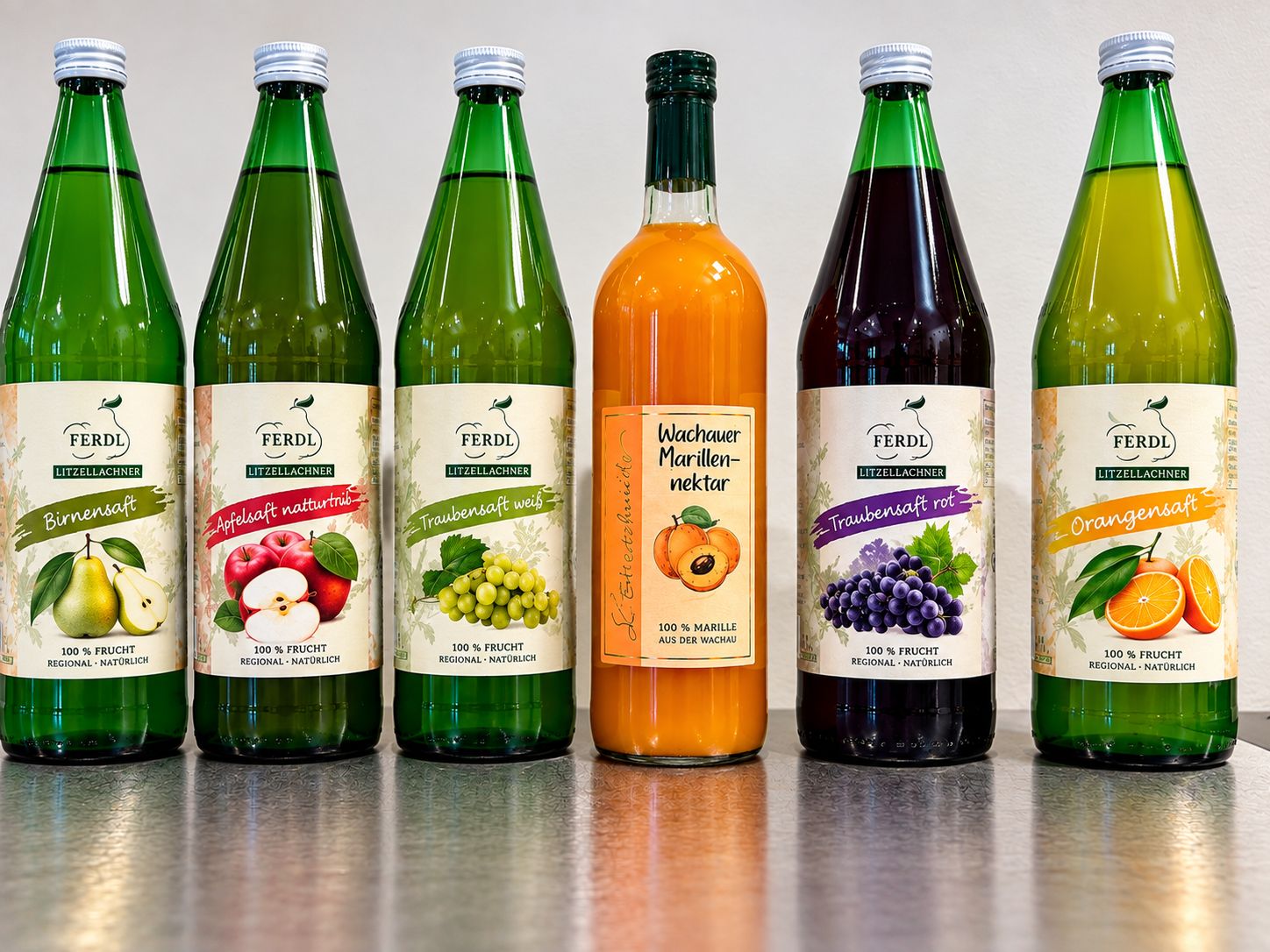 Six bottles of FERDL brand beverages with fruit labels, arranged on a table.