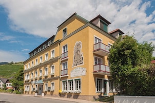 A yellow building with a sign reading "RESTAURANT HOTEL" and balconies with red railings.
