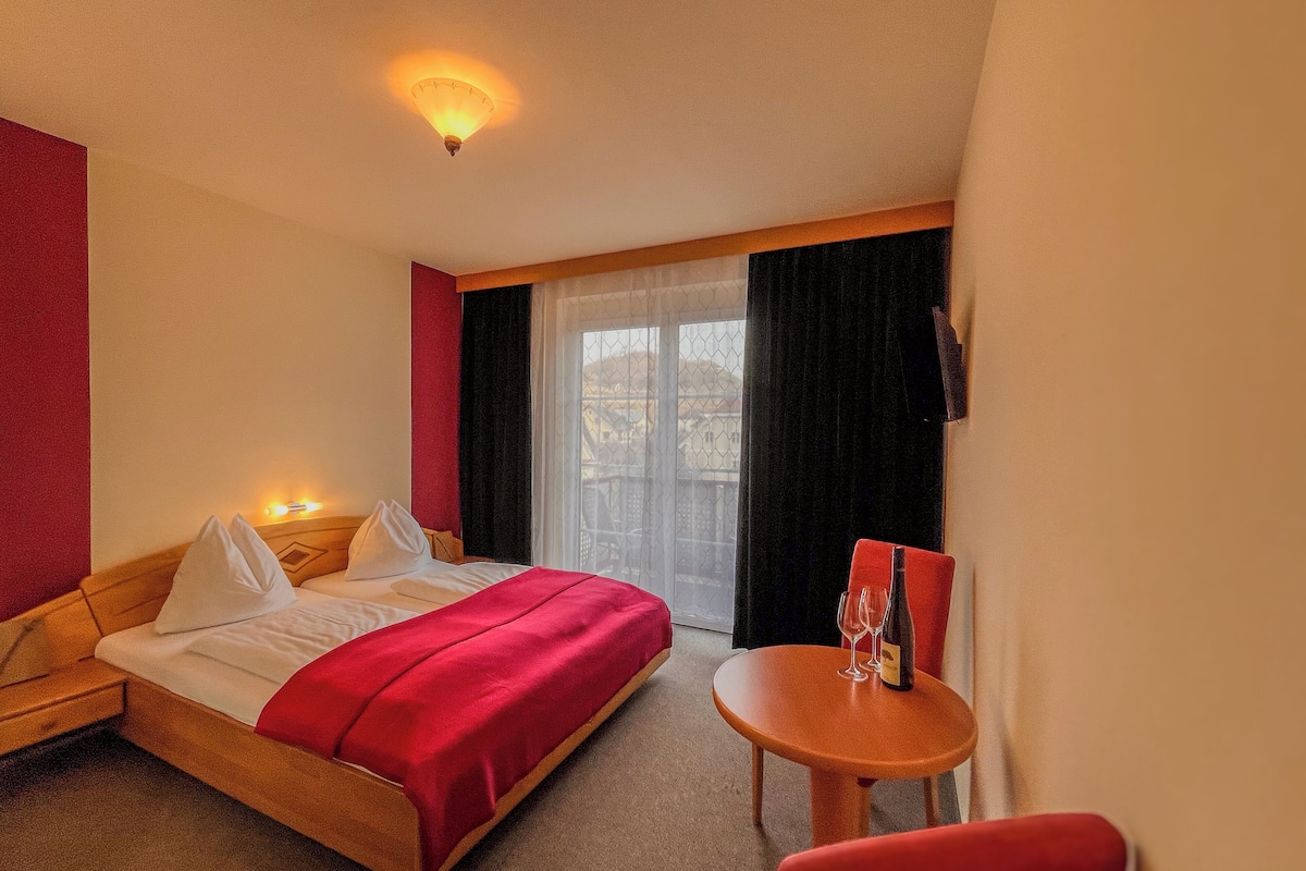 Ein Hotelzimmer mit einem Bett, einem kleinen Tisch mit einem Weinglas und einem Sessel.