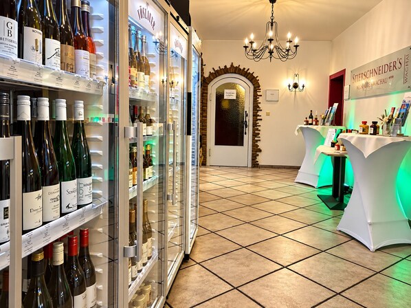 A hotel lobby with a wine cooler, a chandelier, and a reception area with tables. - STIERSCHNEIDERS Weinhotel Wachau (Spitz)