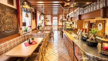 A restaurant interior with wooden booths, a bar area, and a tiled floor.