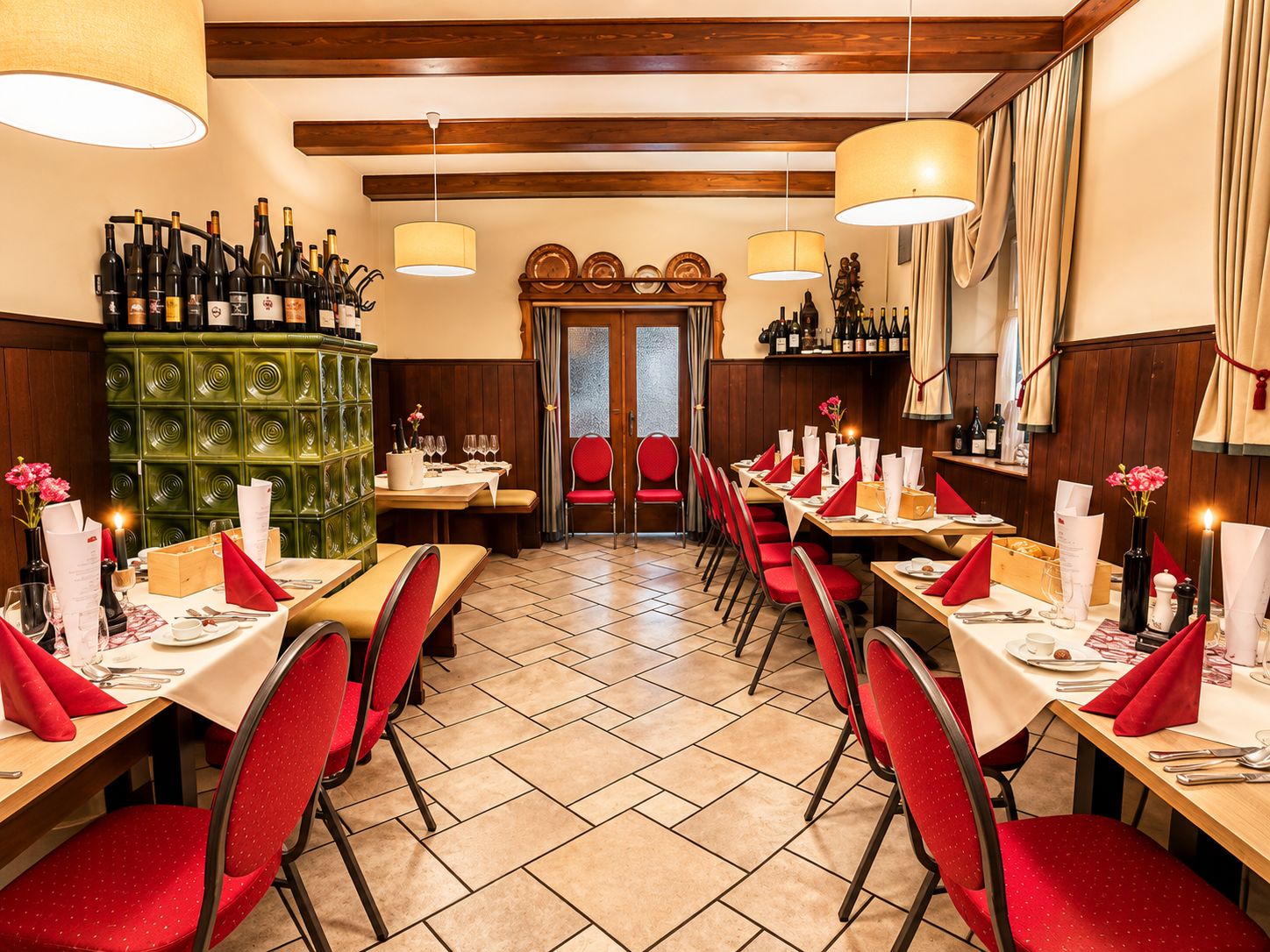 A restaurant interior with multiple dining tables, red chairs, and a green decorative wall.