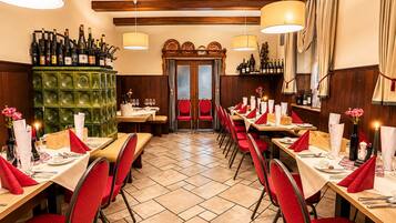 A restaurant interior with multiple dining tables, red chairs, and a green decorative wall.