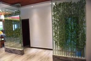 Una habitación con separador de vidrio, base de ladrillo y decoración de pared de bambú.