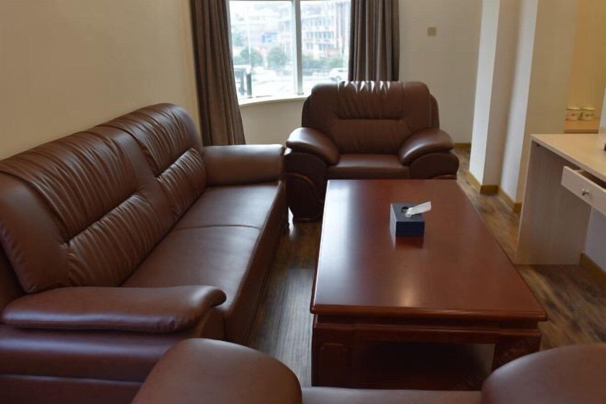 A room with a brown leather sofa, a wooden coffee table, and a desk with a chair.