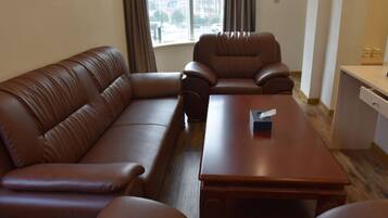 Una habitación con un sofá de cuero marrón, una mesa de centro de madera y un escritorio con una silla.
