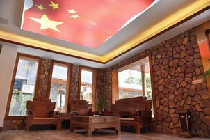 Un vestíbulo con pared de piedra, muebles de madera y una bandera.