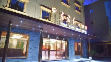 A hotel with a prominent entrance, a covered outdoor area, and a visible sign with Chinese characters.