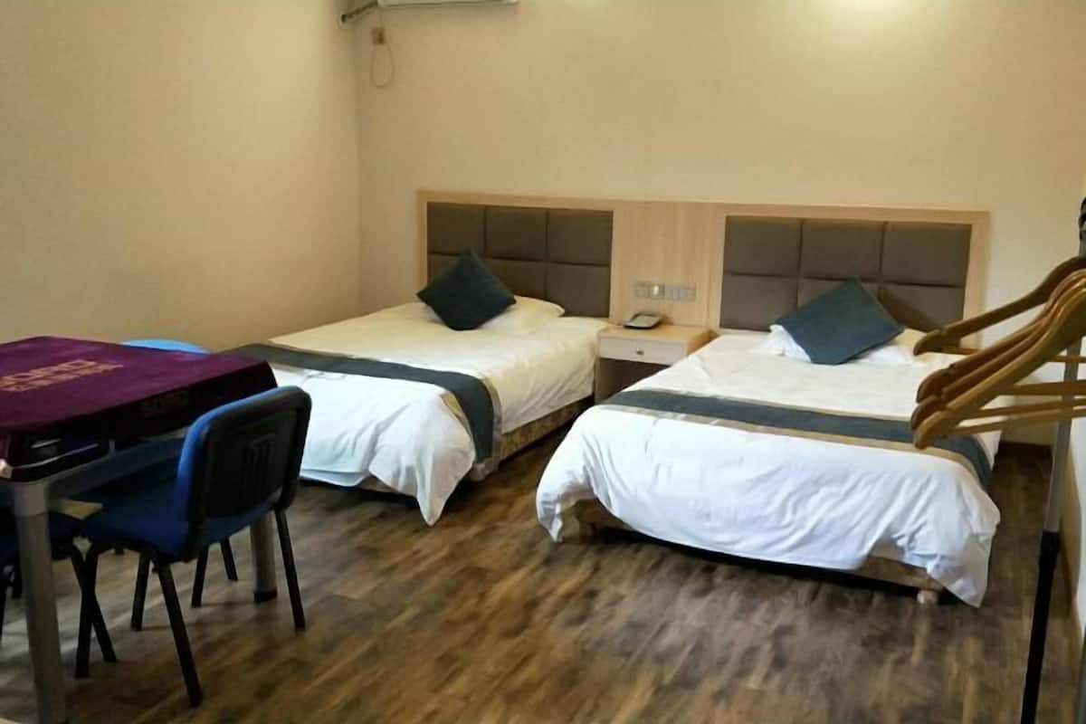 Quarto de hotel com duas camas, uma escrivaninha e uma cadeira.