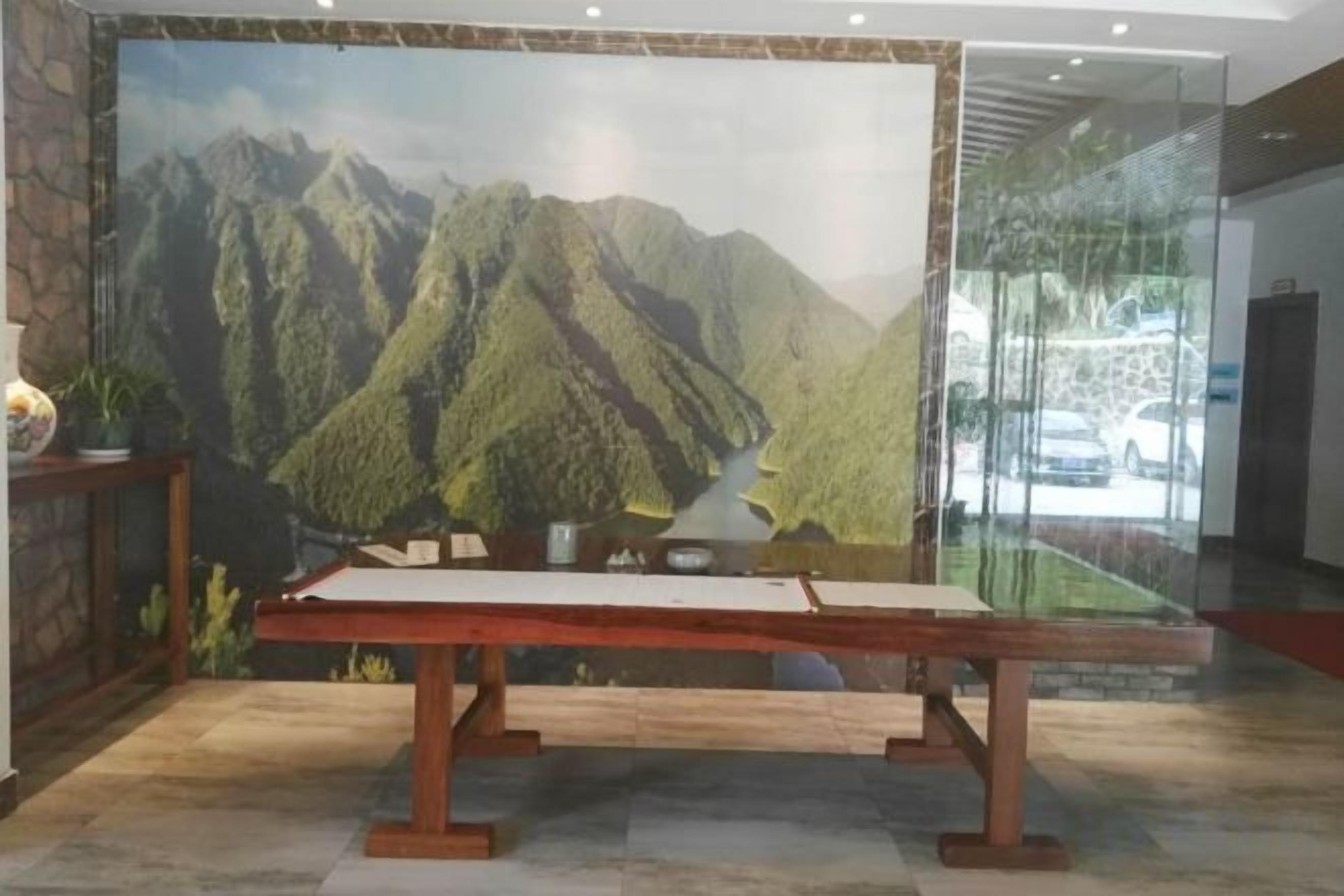 A reception area with a large mountain landscape mural, a reception desk, and a glass partition.