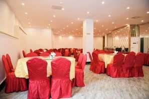 A banquet hall with round tables and red chairs, a marble floor, and a modern chandelier. - Jinggangshan Oriental Red Hotel (Jinggangshan City)