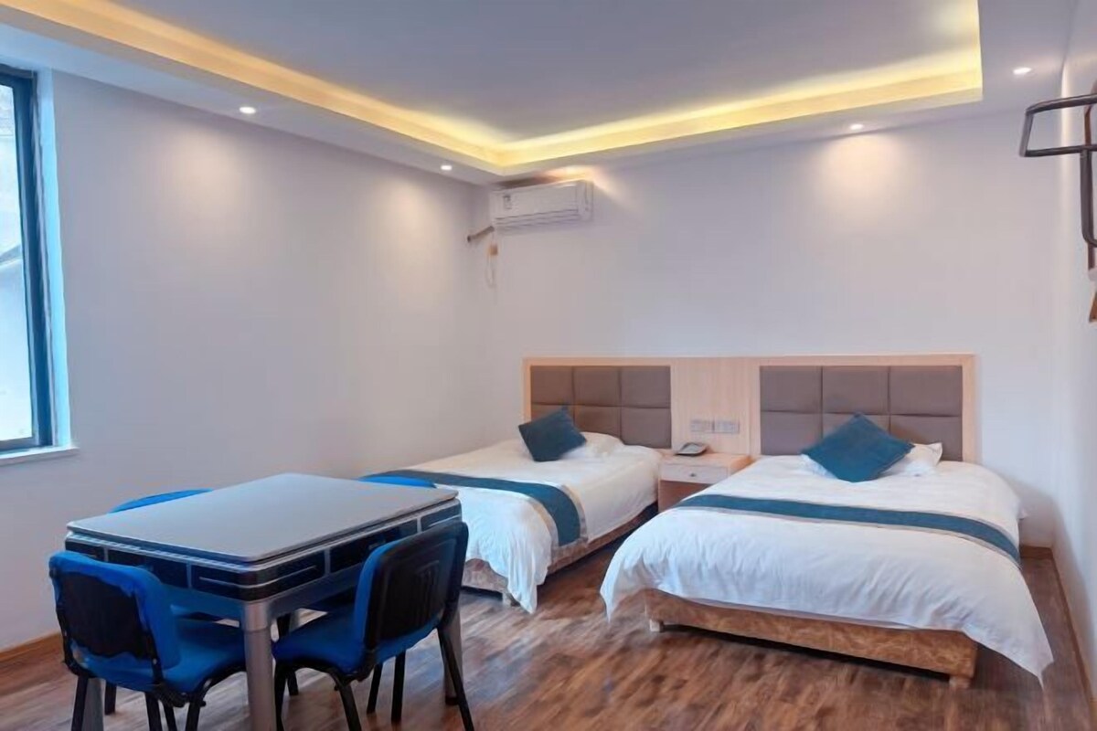 Quarto de hotel com duas camas, uma escrivaninha e cadeiras.