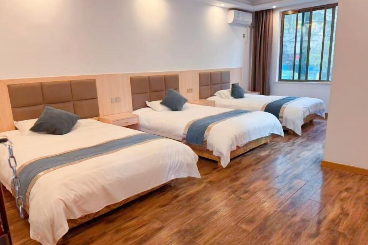 Quarto de hotel com duas camas, piso de madeira e janela com cortinas.