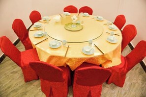 A round table with a yellow tablecloth, surrounded by red chairs. - Jinggangshan Oriental Red Hotel (Jinggangshan City)